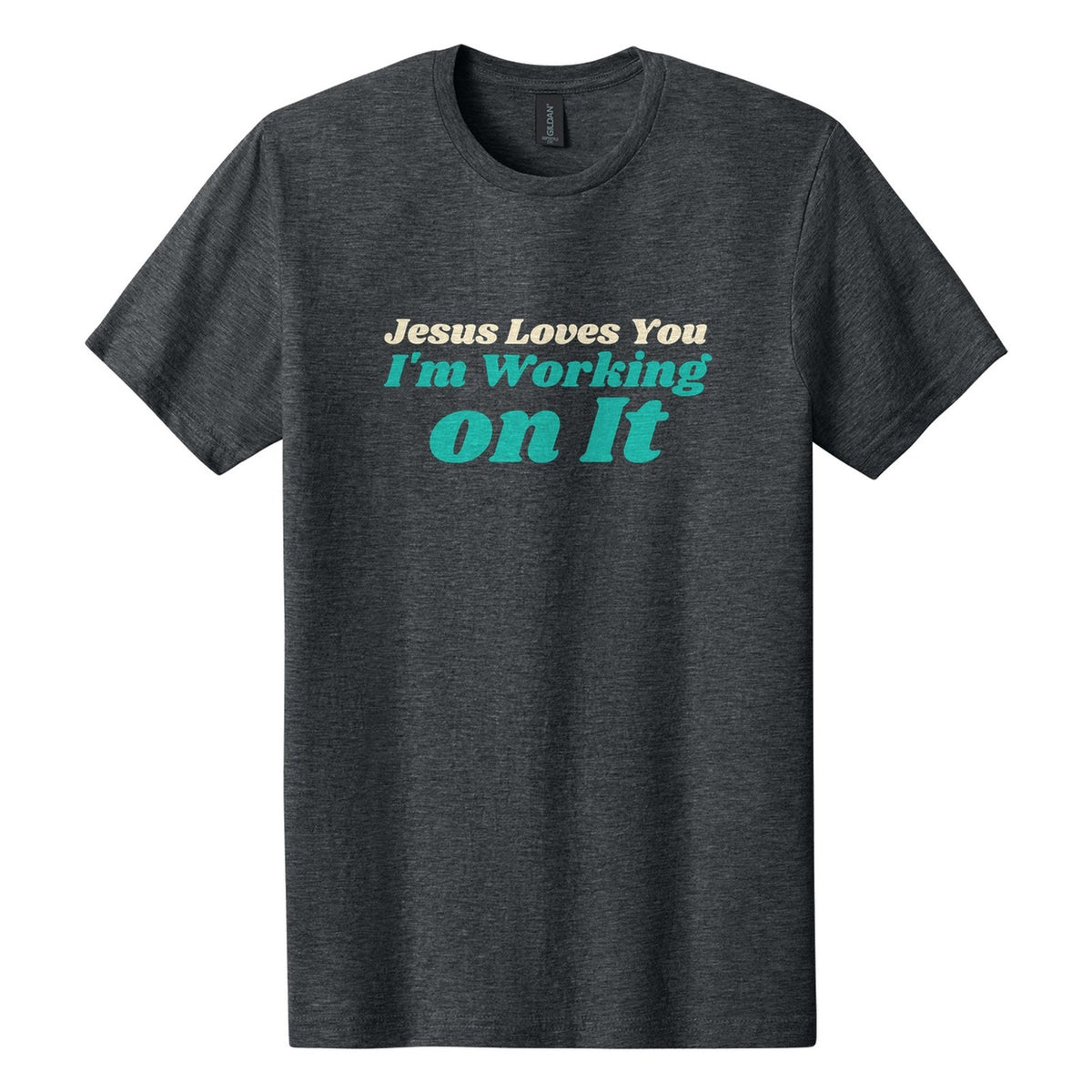 Jesus Loves You. I'm Working on It tee in Dark Heather, Shrikhand font, Cream + Teal ink